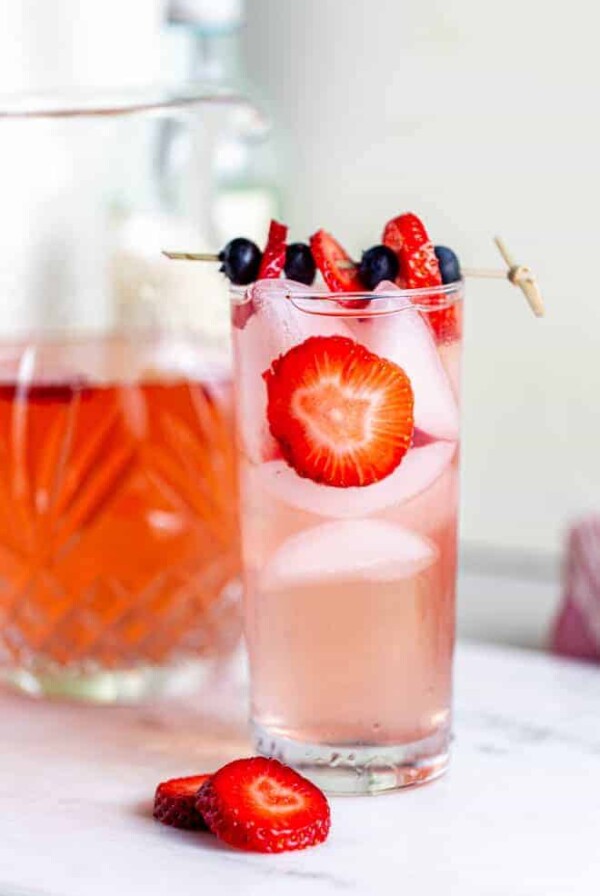 A large glass of strawberry sangria with fresh strawberry slices.