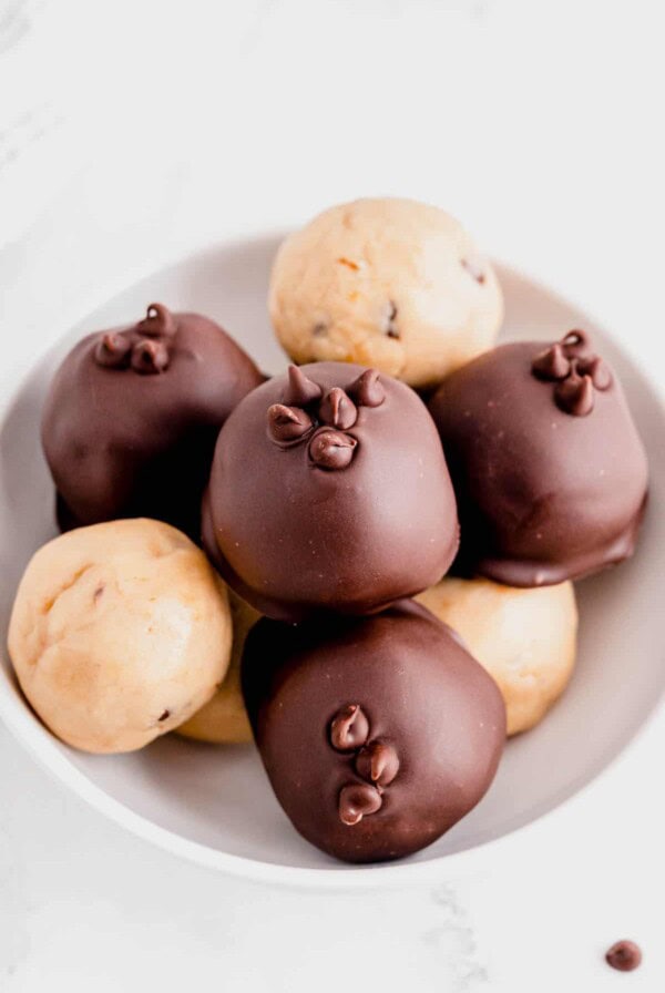 a bowl of cookie dough truffles sitting on a white countertop