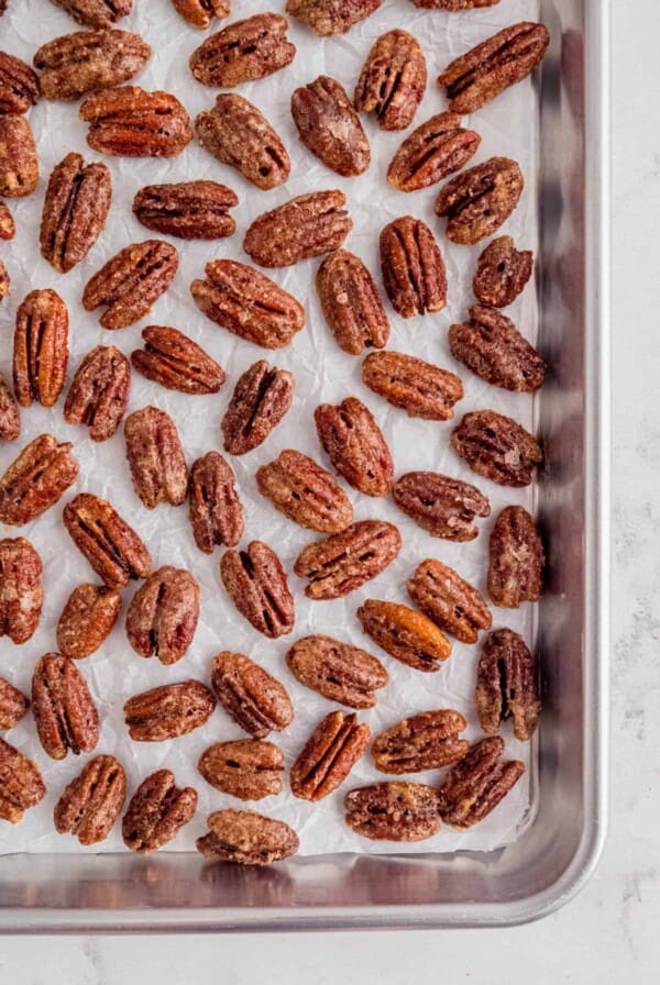 candied pecans on a piece of white parchment paper on a baking sheet