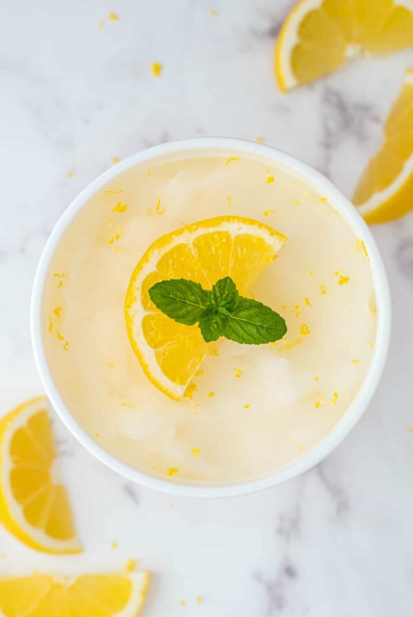 a container of lemon sorbet with a sprig of mint on top