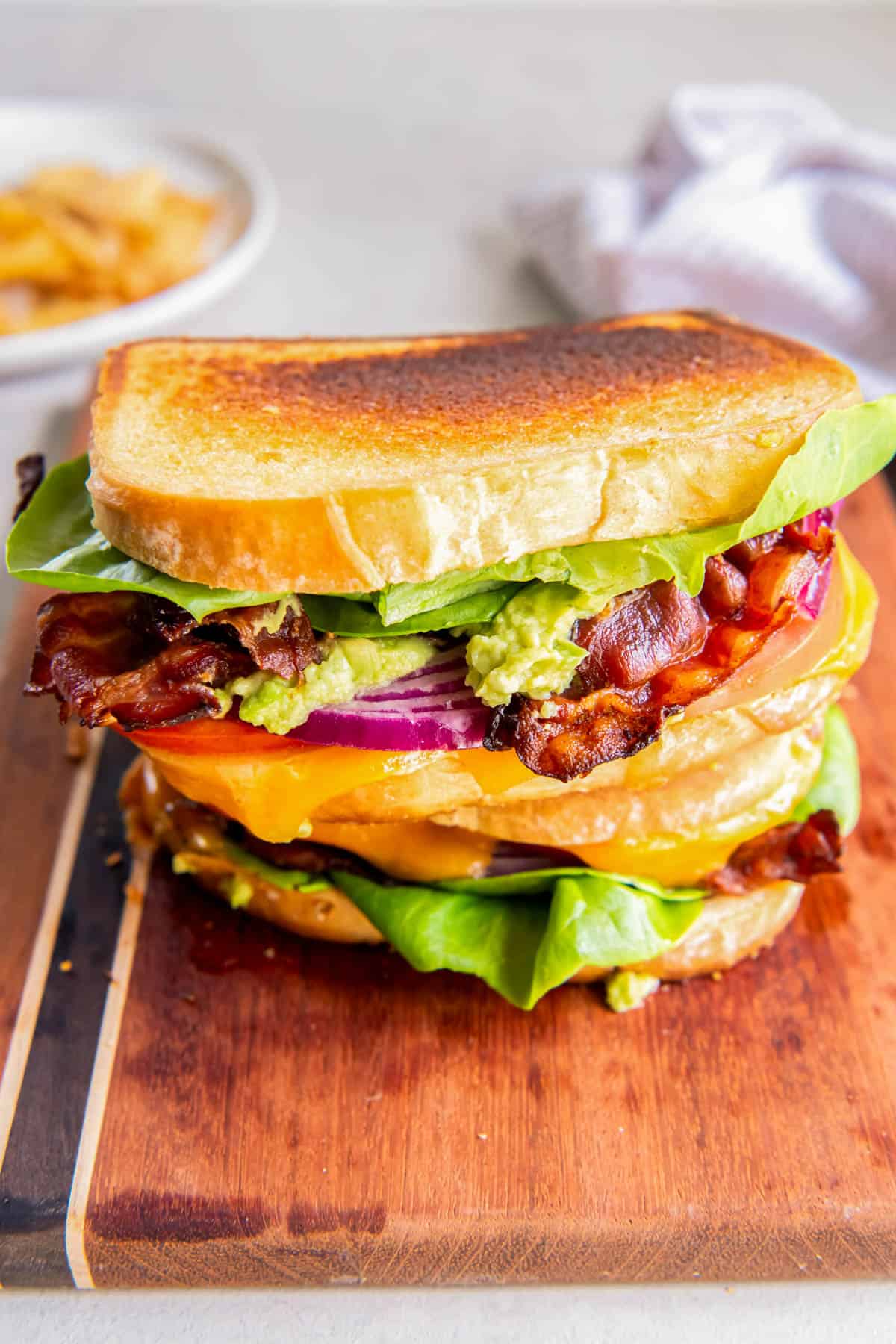 A BLT grilled cheese sandwich with lettuce, tomato, red onion, cheddar cheese, guacamole and chipotle mayo. 