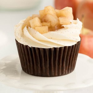 One apple pie cupcake sitting on a white cupcake stand for serving.