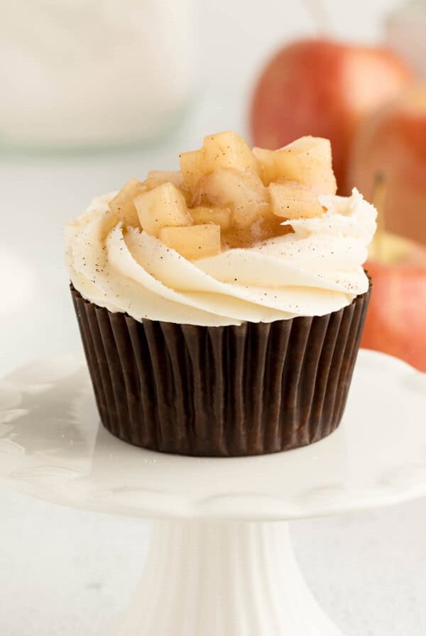 One apple pie cupcake sitting on a white cupcake stand for serving.