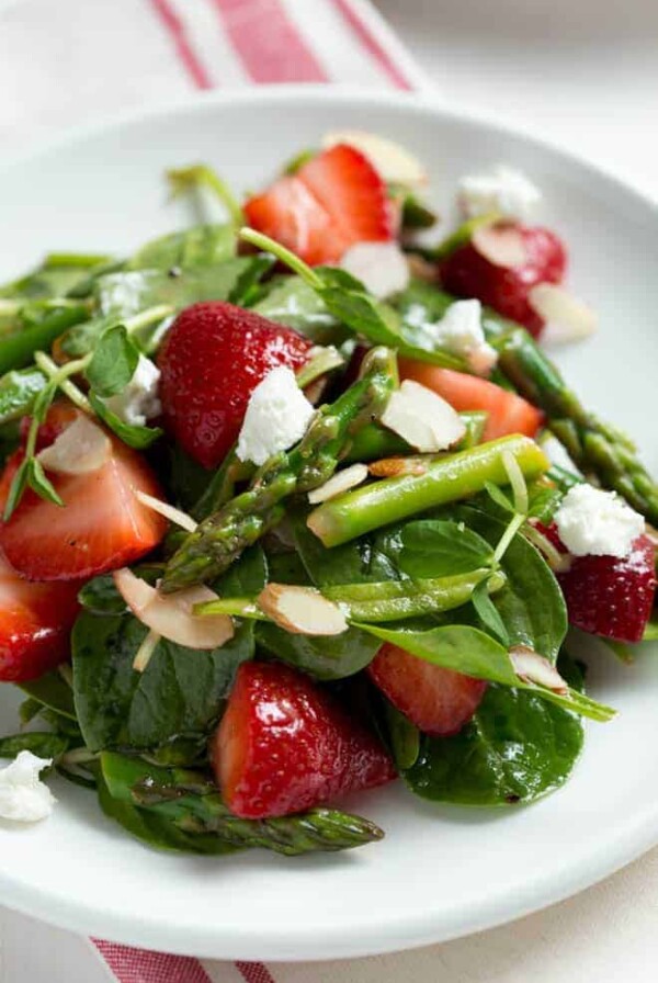 A large plate of spinach and strawberry salad.