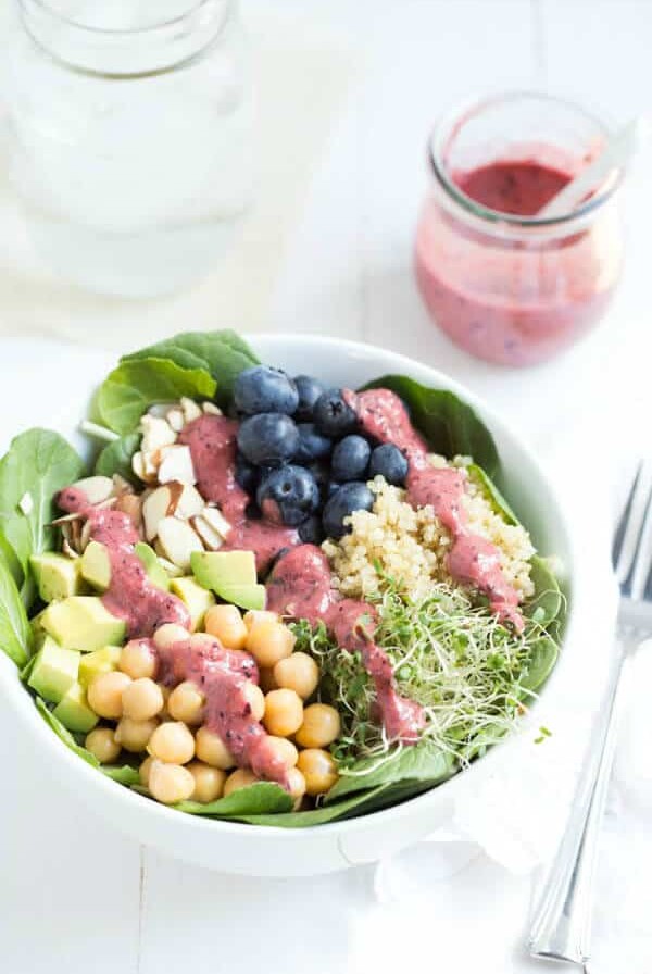 Spring Superfood Bowl with Blueberry-Ginger Dressing - a bed of fresh greens is topped with blueberries, quinoa, sprouts, chickpeas, avocado, almonds and blueberry-ginger dressing!