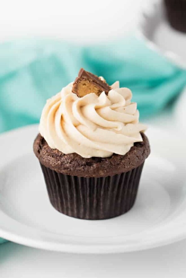 one chocolate peanut butter cupcake with frosting sitting on a white plate