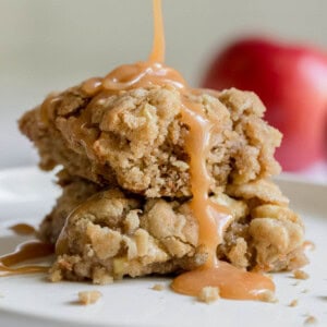 Two pieces of caramel apple cake on a plate with caramel sauce pouring down the sides.