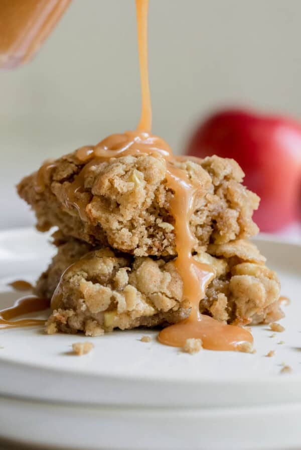 Two pieces of caramel apple cake on a plate with caramel sauce pouring down the sides.