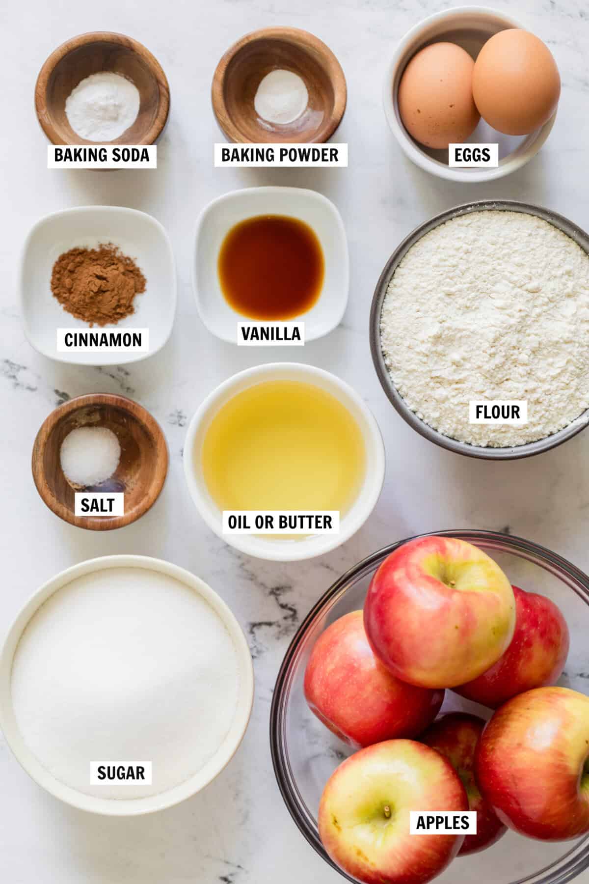 All of the ingredients for caramel apple cake in bowls on countertop.