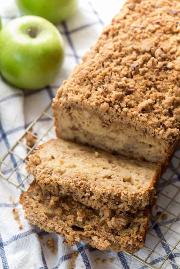 a loaf of apple cinnamon bread with two slices sitting next to it on a baking rack