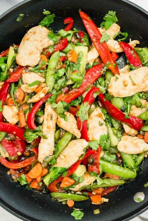 cooked chicken teriyaki stir fry garnished with cilantro sitting in a black nonstick skillet