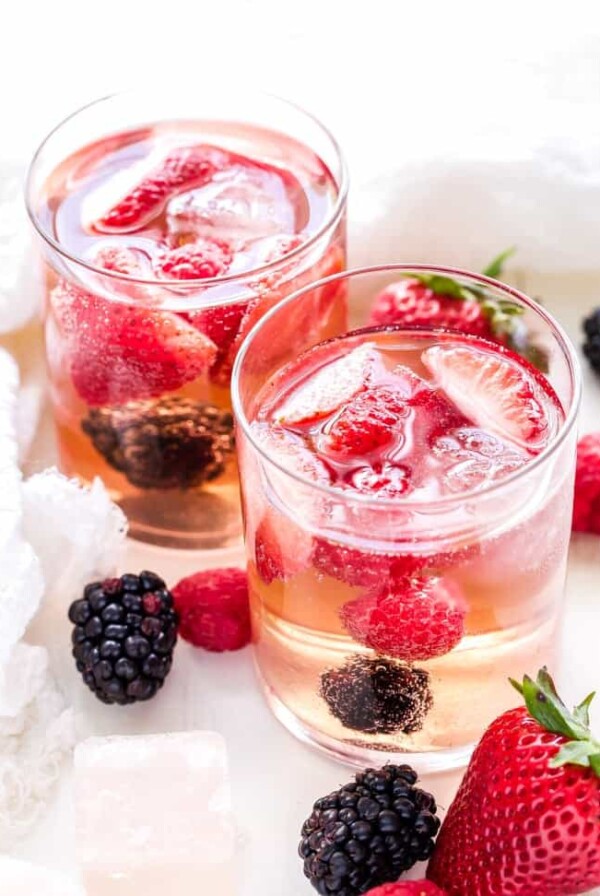 two clear glasses filled with rose sangria and fresh strawberries and blackberries