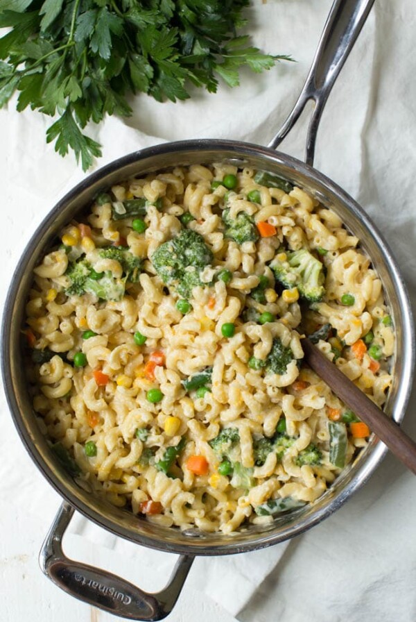 A large pan of veggie mac and cheese with a spoon in it.