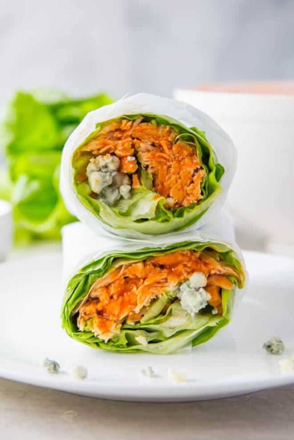 Two buffalo lettuce chicken wraps stacked on top of each other on a white background.