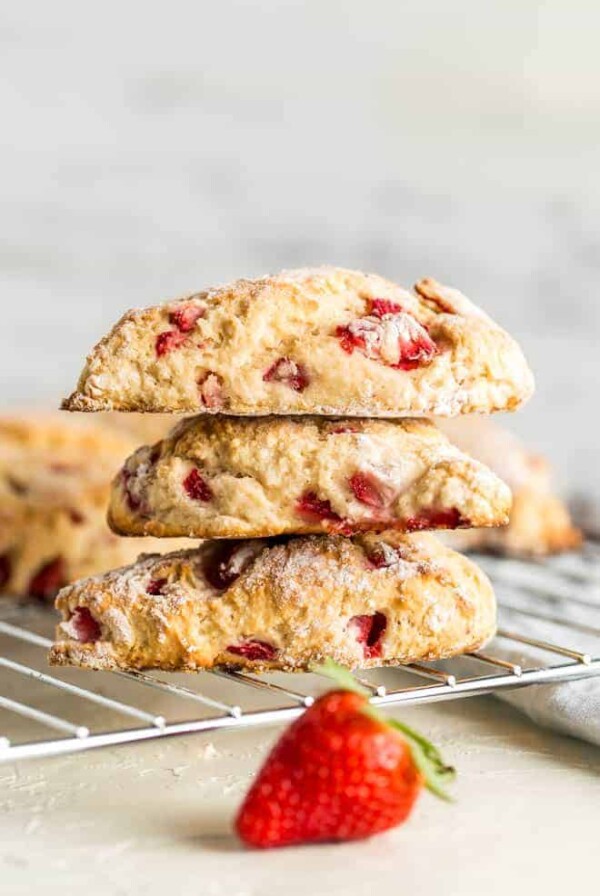 A pile of three strawberry scones sitting on a cooling rack.