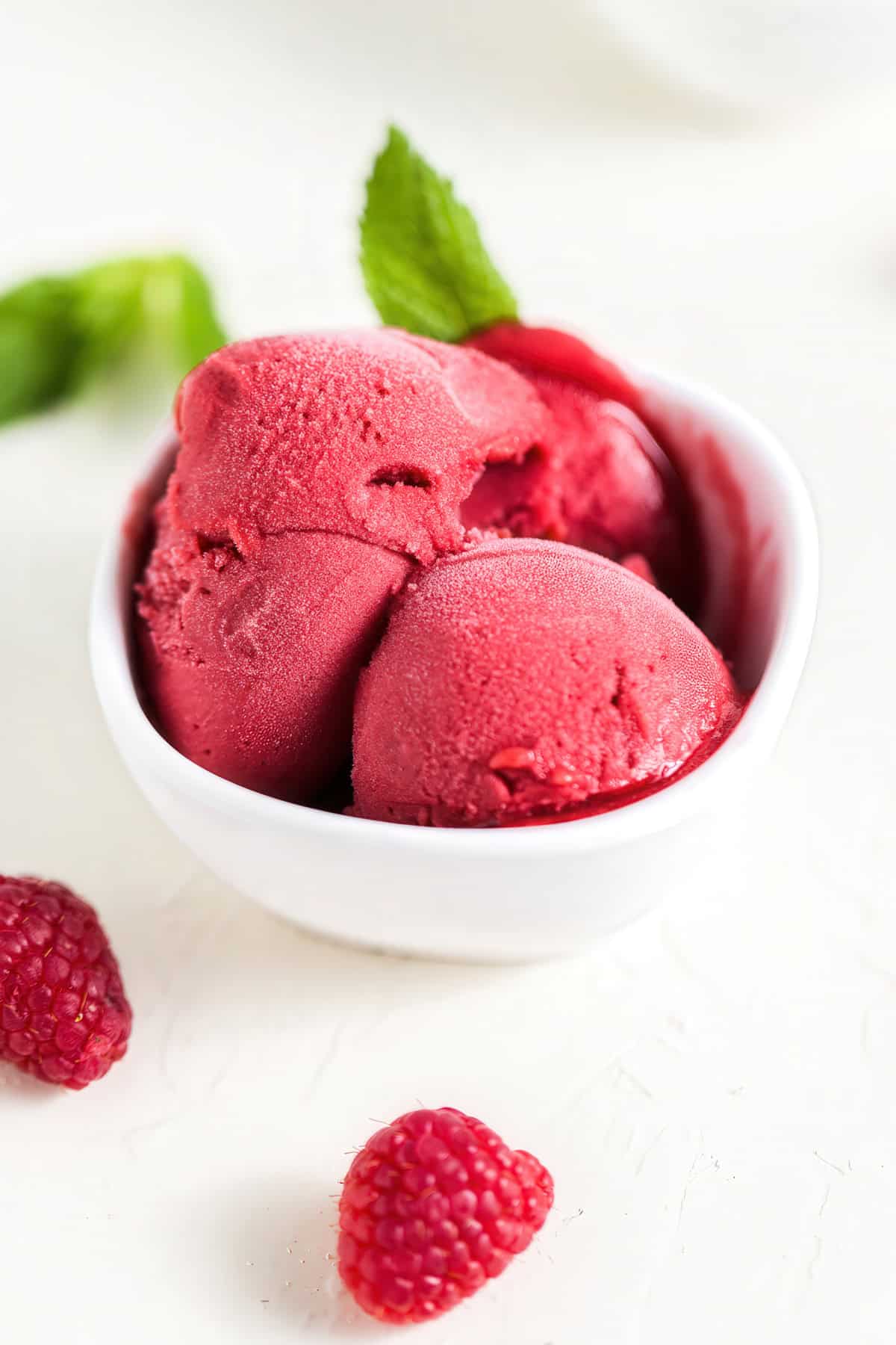 Three scoops of raspberry mint sorbet garnished with mint leaves.