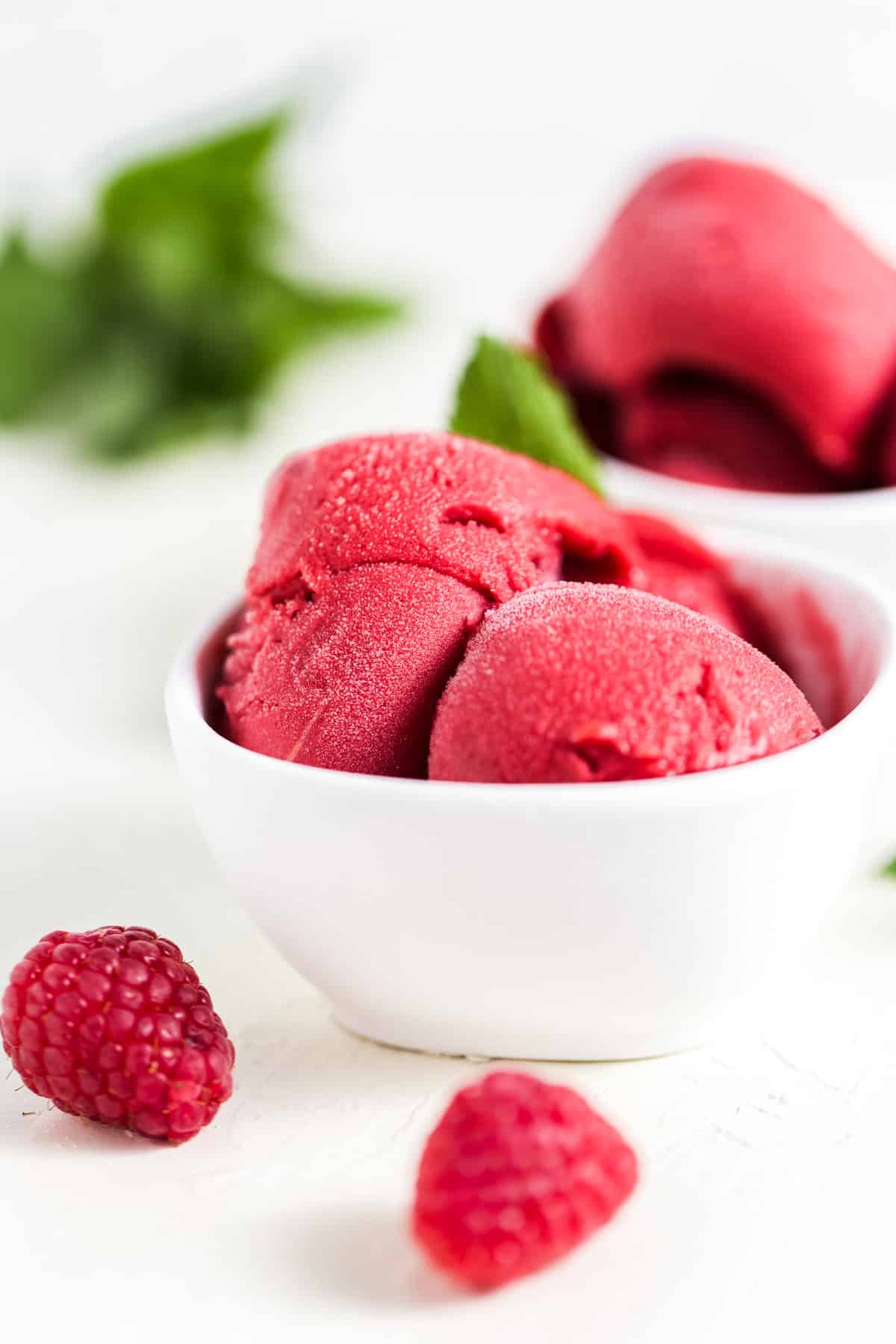 Three scoops of raspberry mint sorbet garnished with mint leaves.