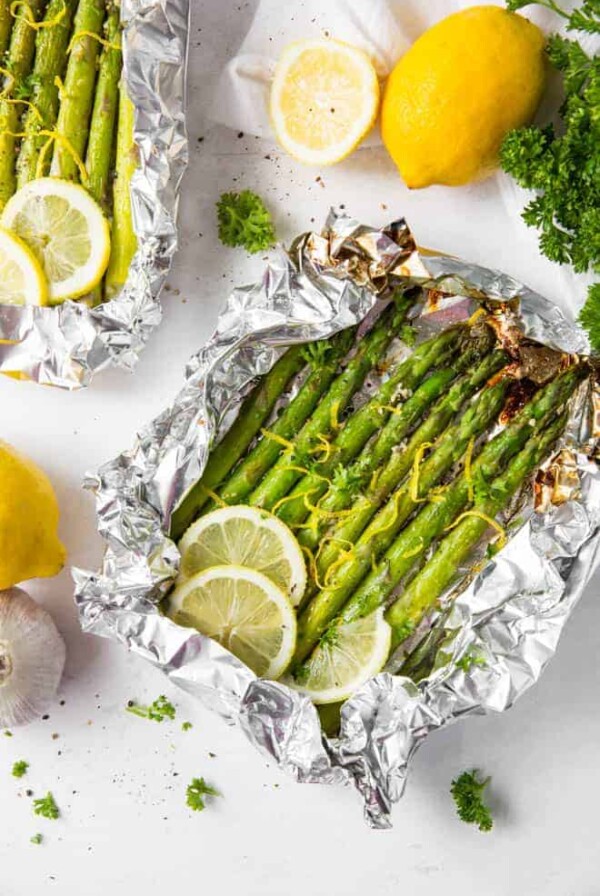 Grilled asparagus in foil with lemon slices and lemon zest.