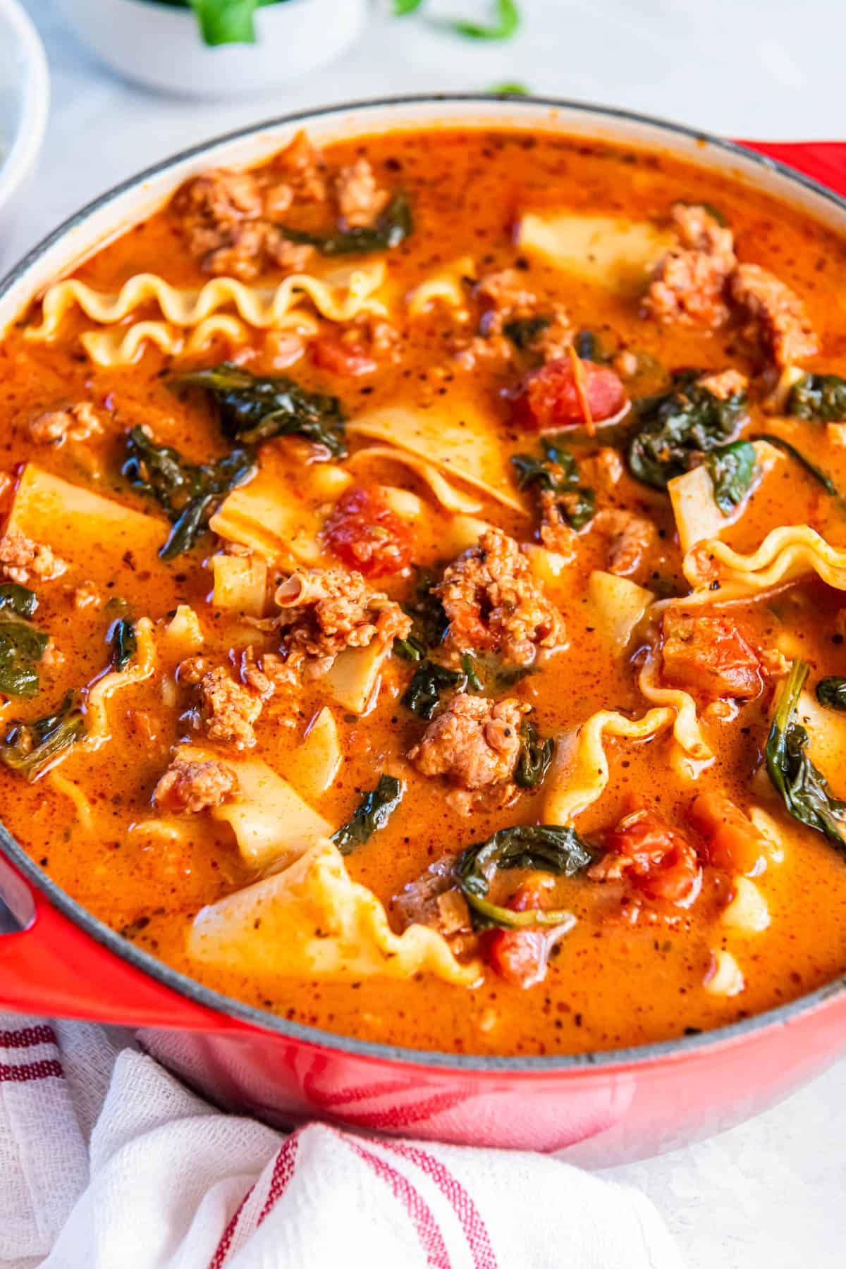 A red Dutch oven filled with lasagna soup that is ready for serving. 