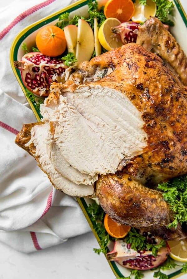 a roasted thanksgiving turkey on a pan with fresh citrus