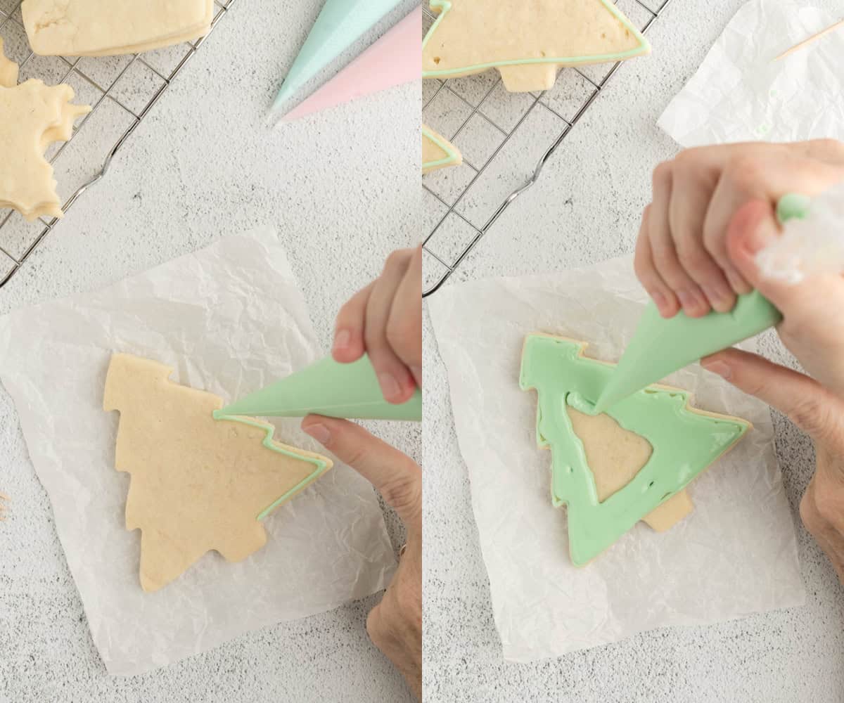 A hand holding a piping bag pipes the edges of a sugar cookie with green icing before flooding the cookie with the remaining icing.