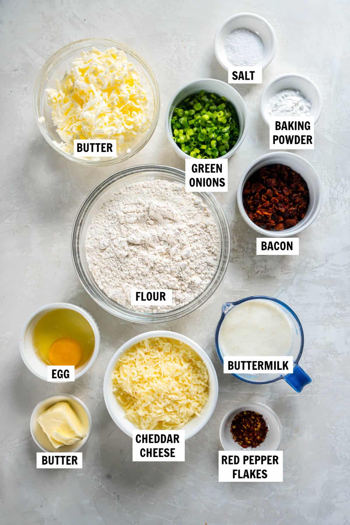 All of the ingredients for cheddar scones with chives in bowls on a countertop. 