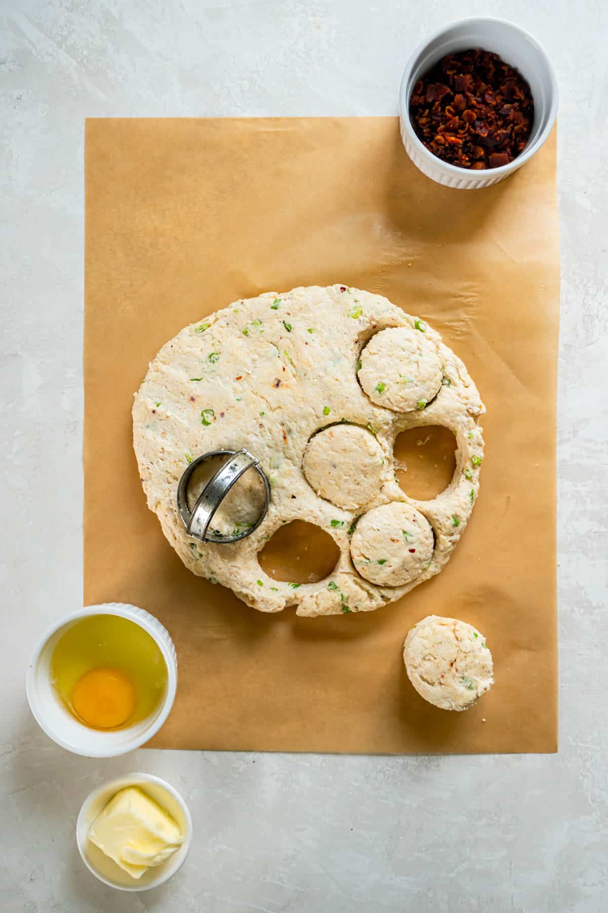 Using a biscuit cutter to cut the scone dough sitting on a piece of parchment paper. 