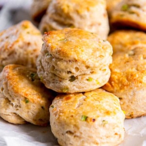 A white plate stacked with cheddar scones with chives.