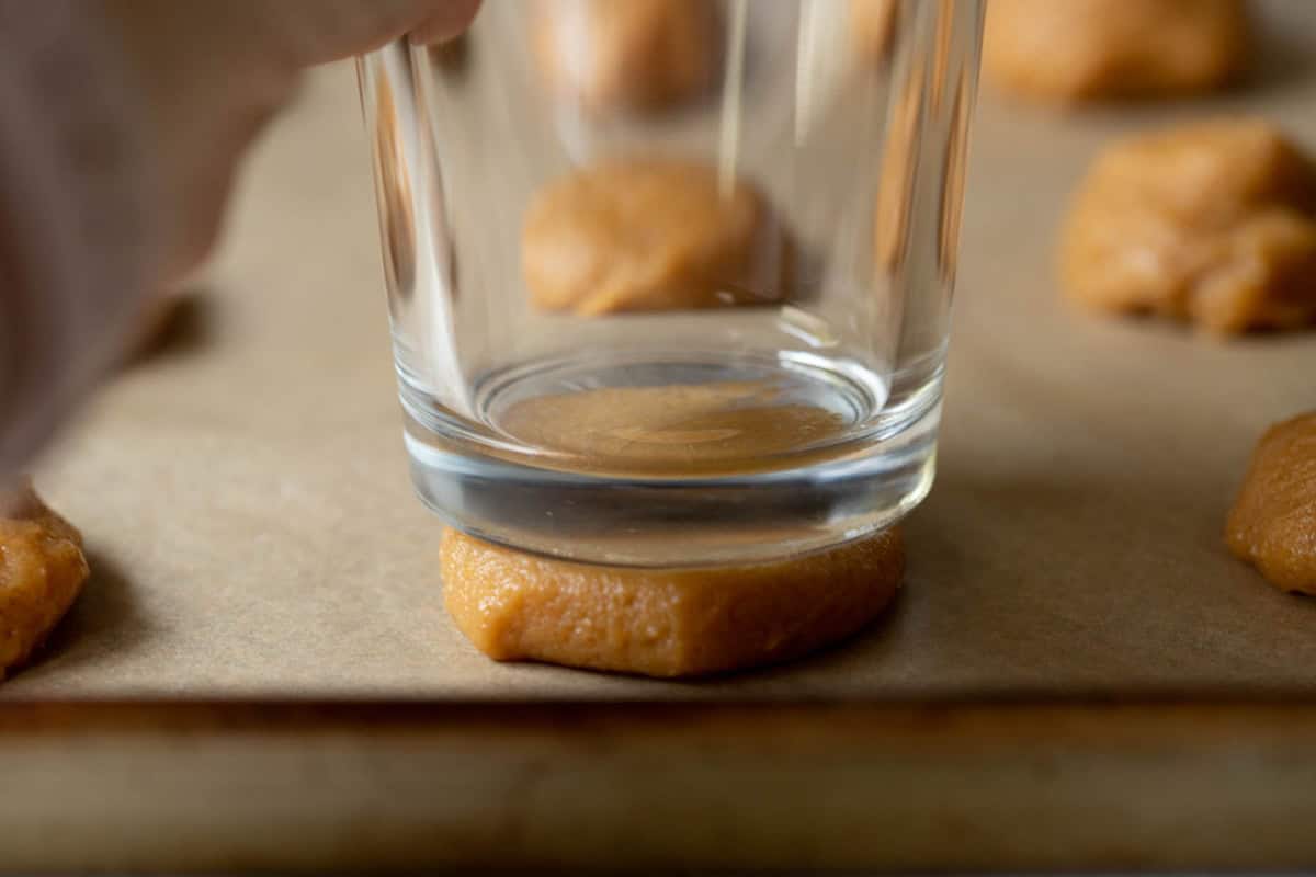 A glass flattening a peanut butter cookie.