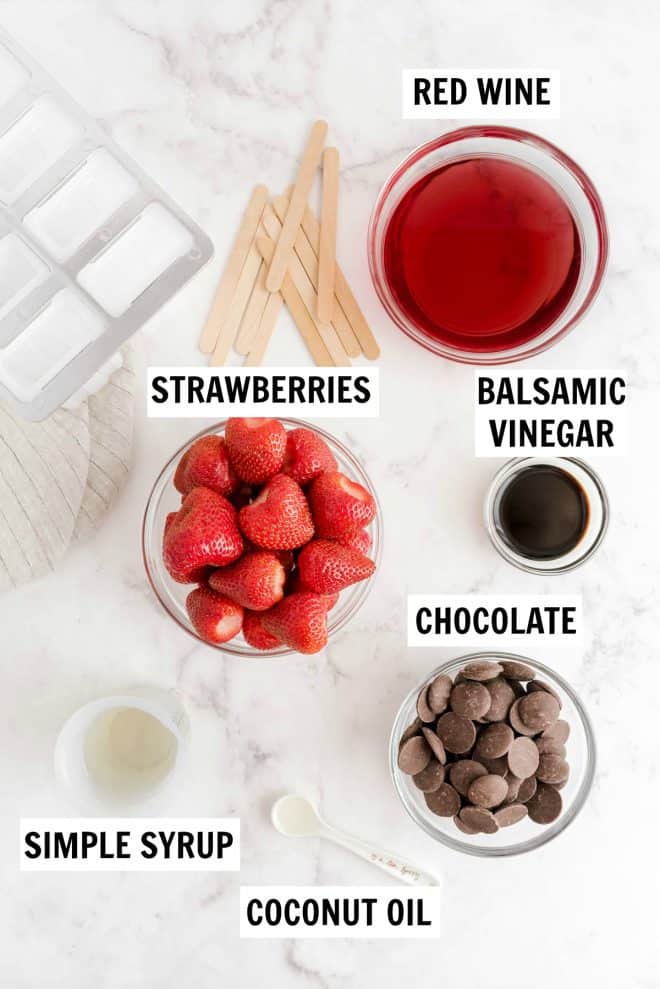 ingredients to make strawberry red wine popsicles sitting on a counter