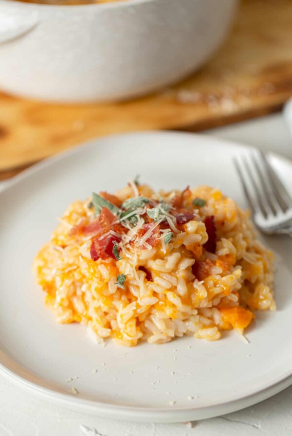 butternut squash risotto with sage and bacon on a white plate