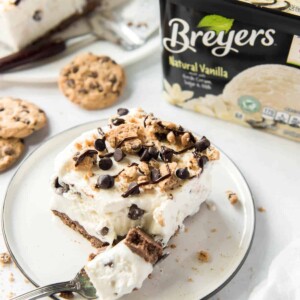 a slice of chocolate chip cookie ice cream cake on a white plate with a fork