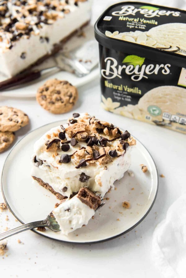 a slice of chocolate chip cookie ice cream cake on a white plate with a fork