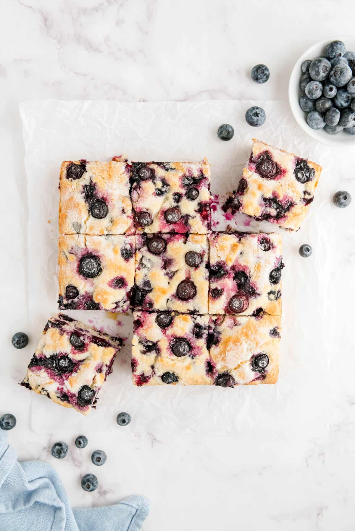 blueberry breakfast cake cut into nine slices on a piece of white parchment paper.