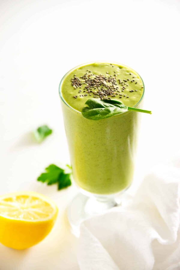 green detox smoothie in a glass cup with chia seeds sprinkled on top