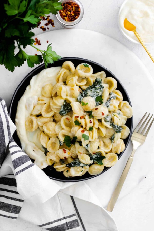 a plate with whipped ricotta and pasta with kale