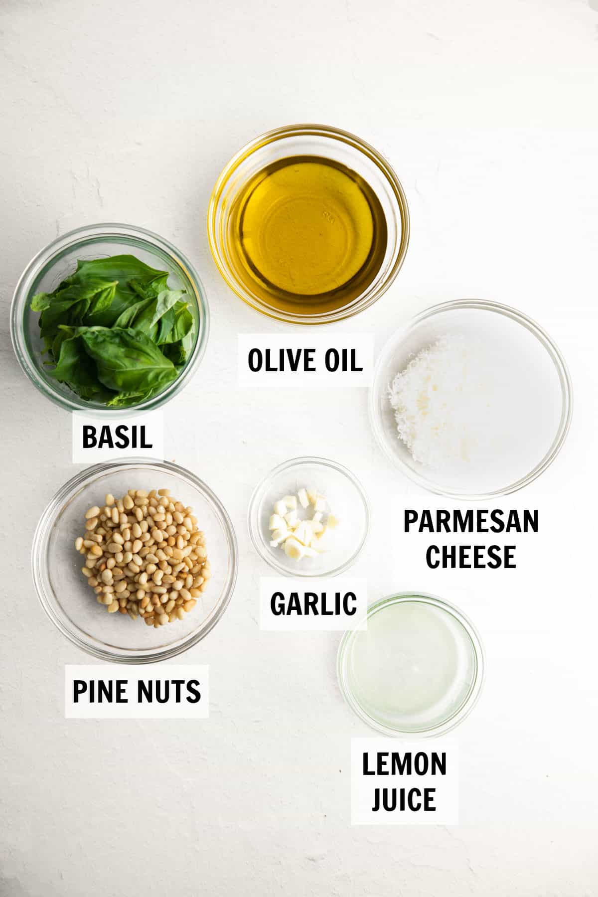 Ingredients for homemade pesto measured in glass bowls