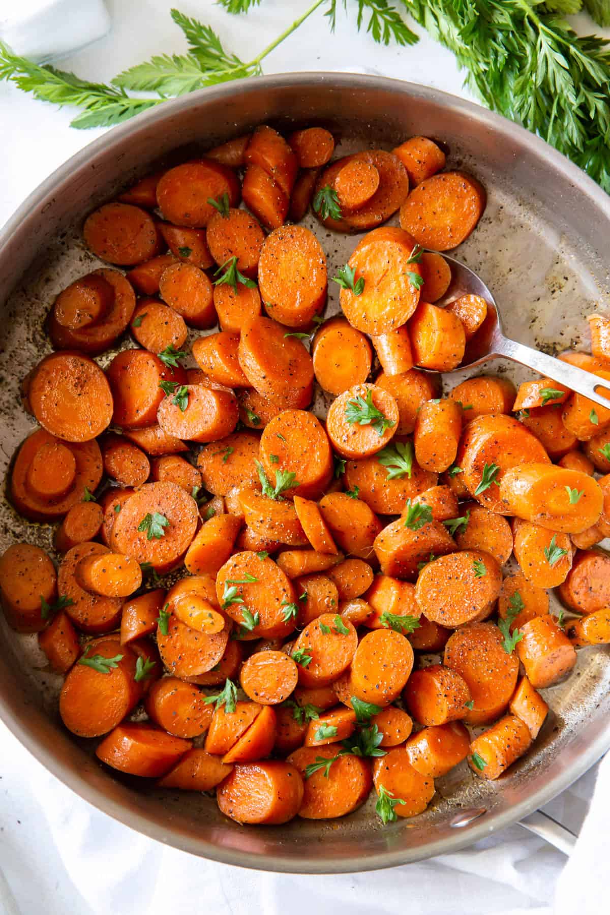 Sauteed carrots topped with parsley in a silver pan