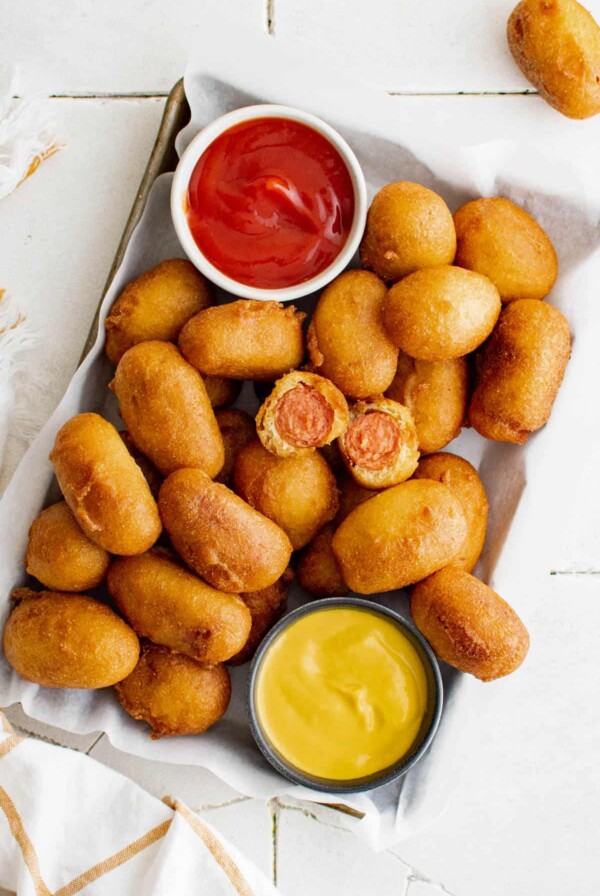 mini corn dogs on a tray with ketchup and mustard