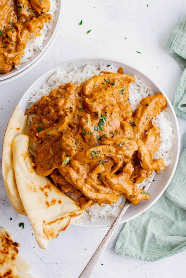 one plate of indian butter chicken with naan bread over rice