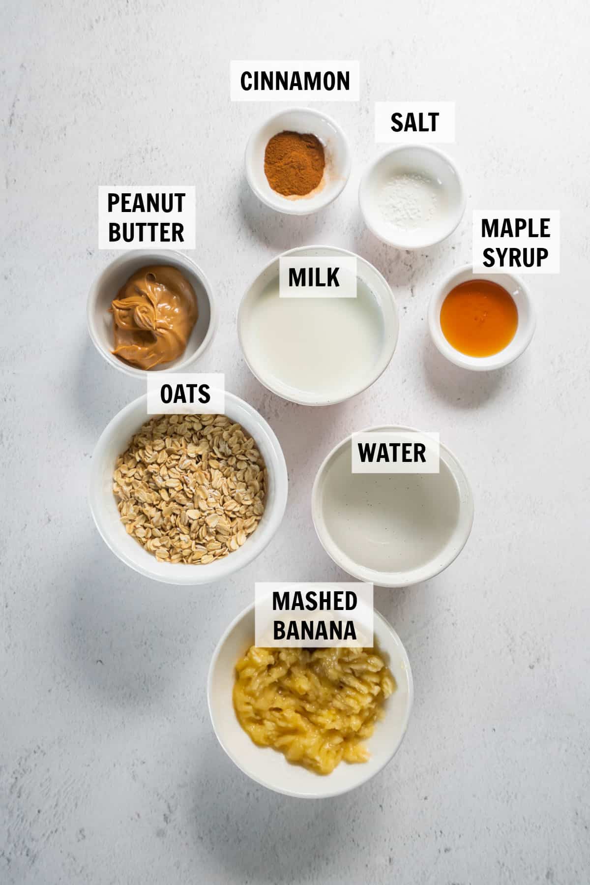 all of the ingredients for peanut butter banana oatmeal on a white countertop