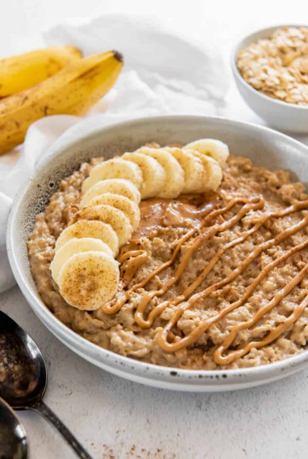 a bowl of peanut butter banana oatmeal with peanut butter sauce drizzled on top