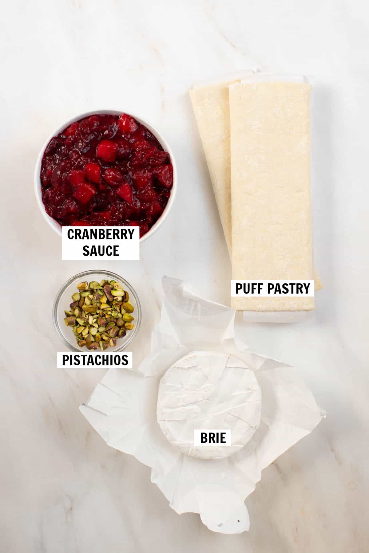 All of the ingredients for cranberry brie bites on a white countertop. 