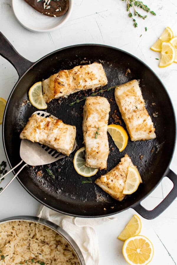 five slices of sea bass in a cast iron pan