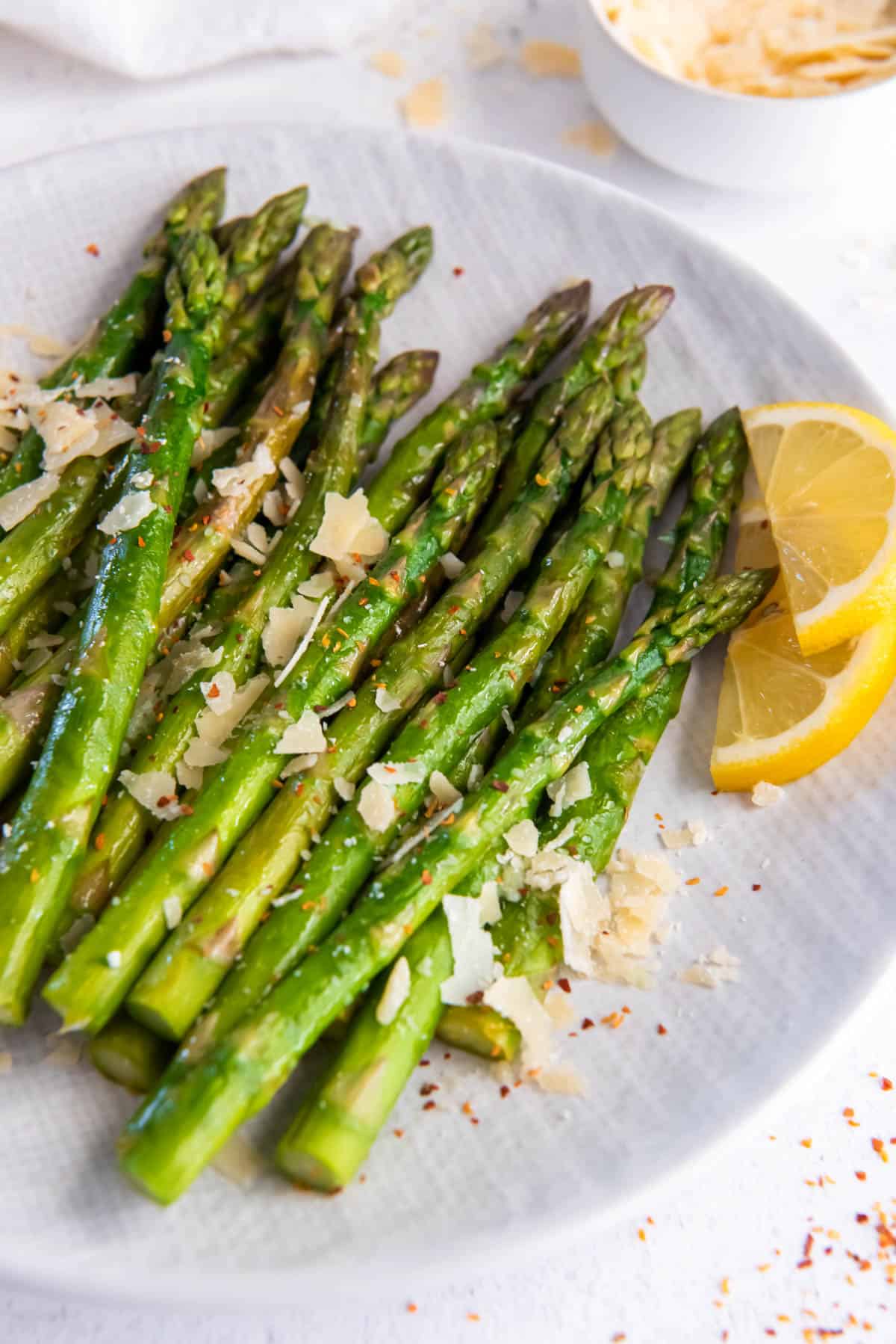 cooked asparagus on a plate with grated parmesan cheese