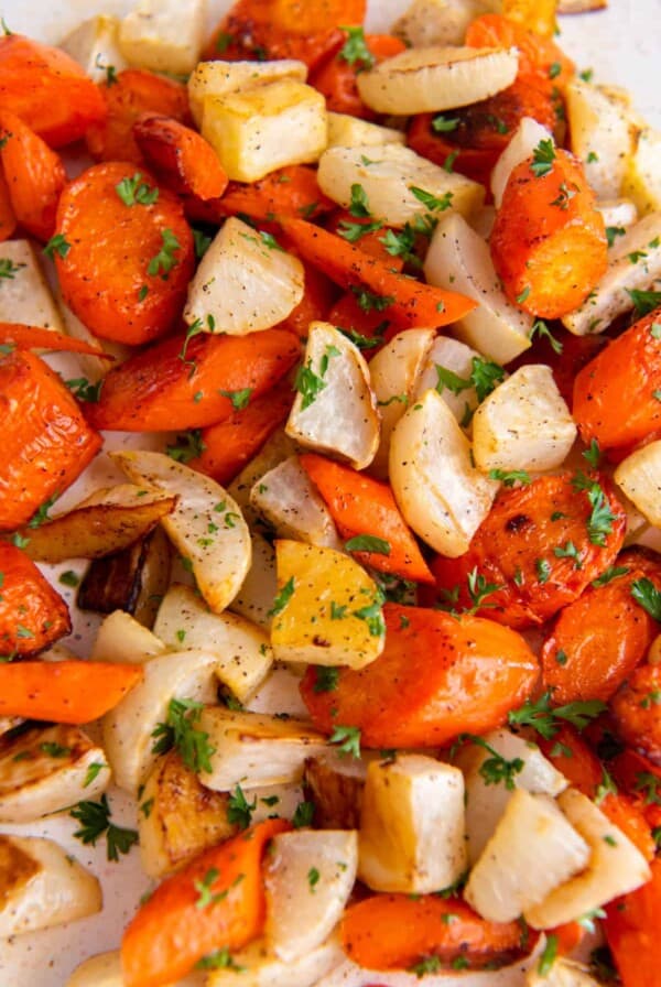 roasted turnips and carrots piles on a sheet pan with chopped parsley