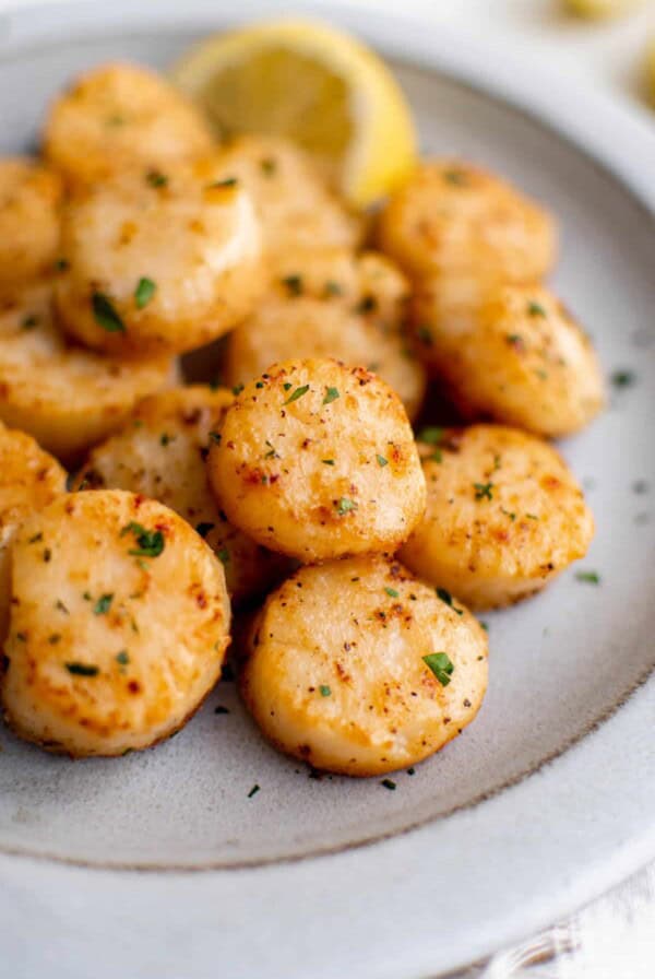 Broiled scallops stacked on a plate.