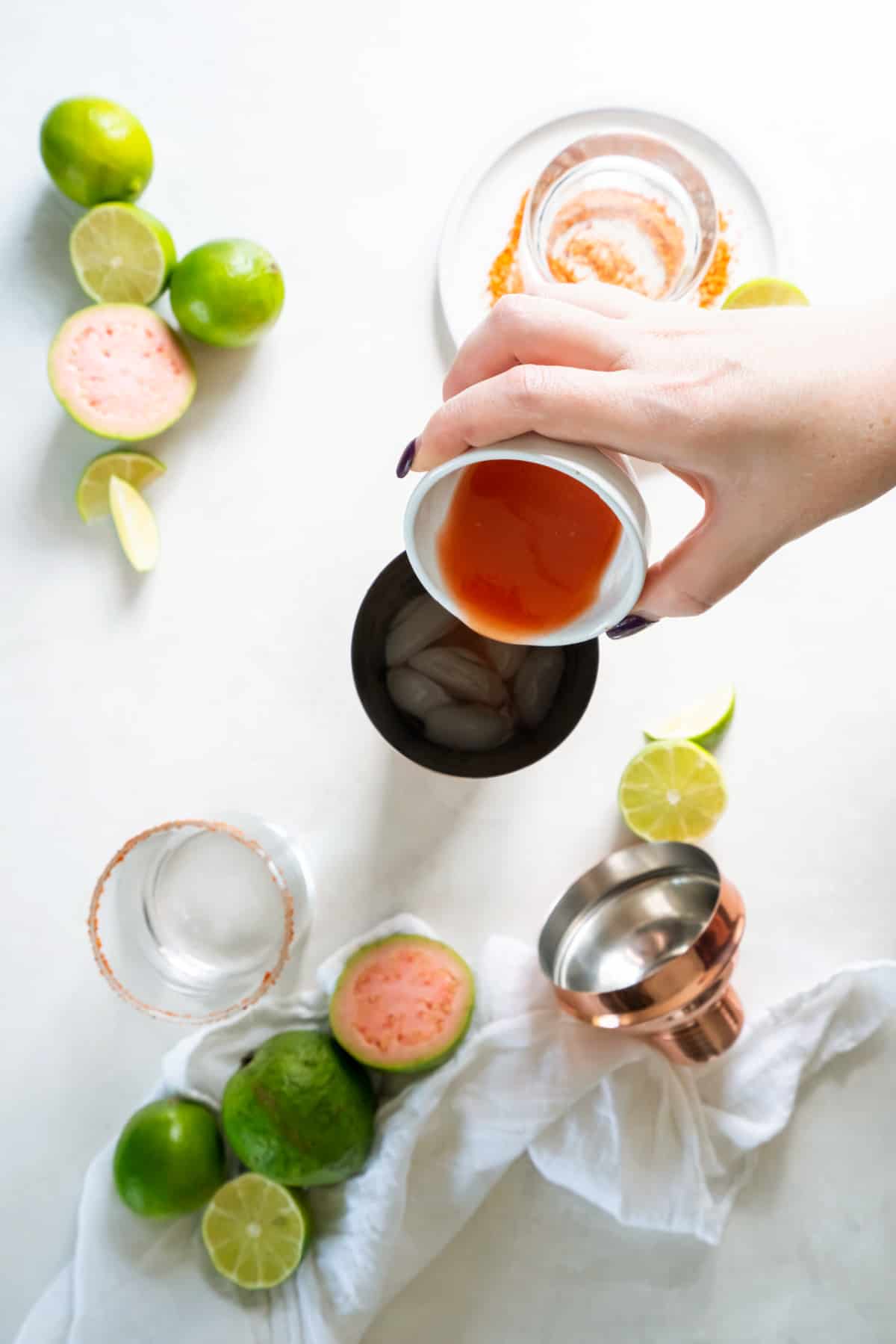 Pouring the ingredients for the guava margarita into a cocktail shaker before mixing.