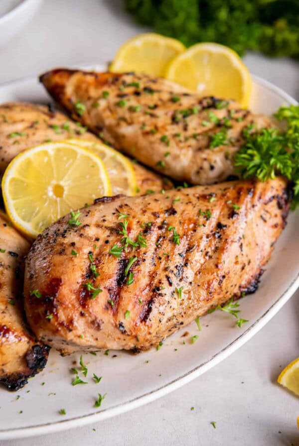 A plate layered with grilled lemon pepper chicken breasts.