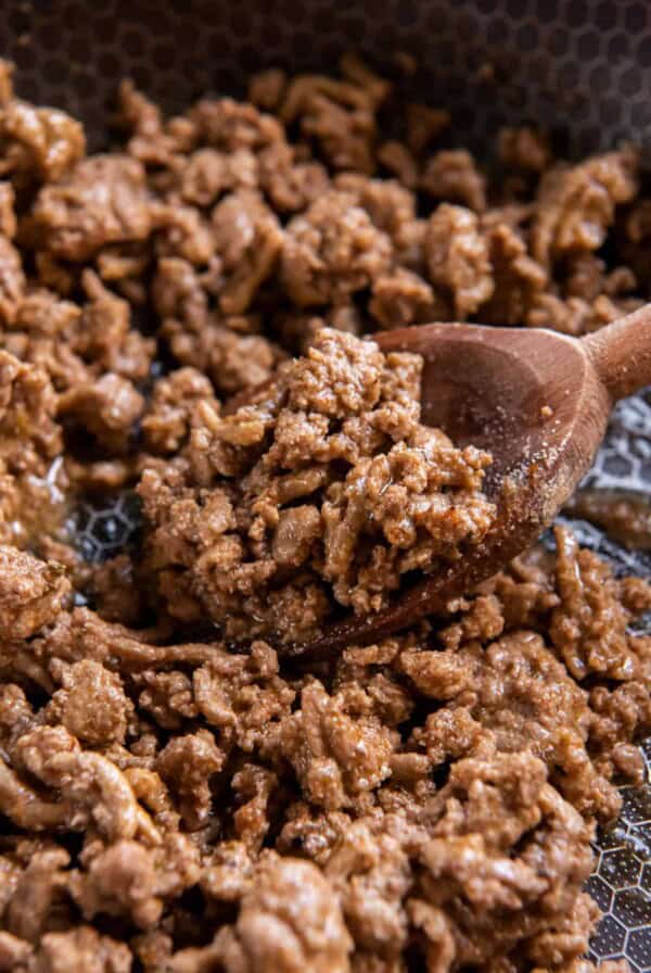 Seasoned ground turkey taco meat in a skillet with a wooden spoon.